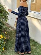 Off-the-Shoulder Maxi Dress in navy blue with white polka dots, long sleeves, and a floor-length flowing silhouette with off-the-shoulder neckline