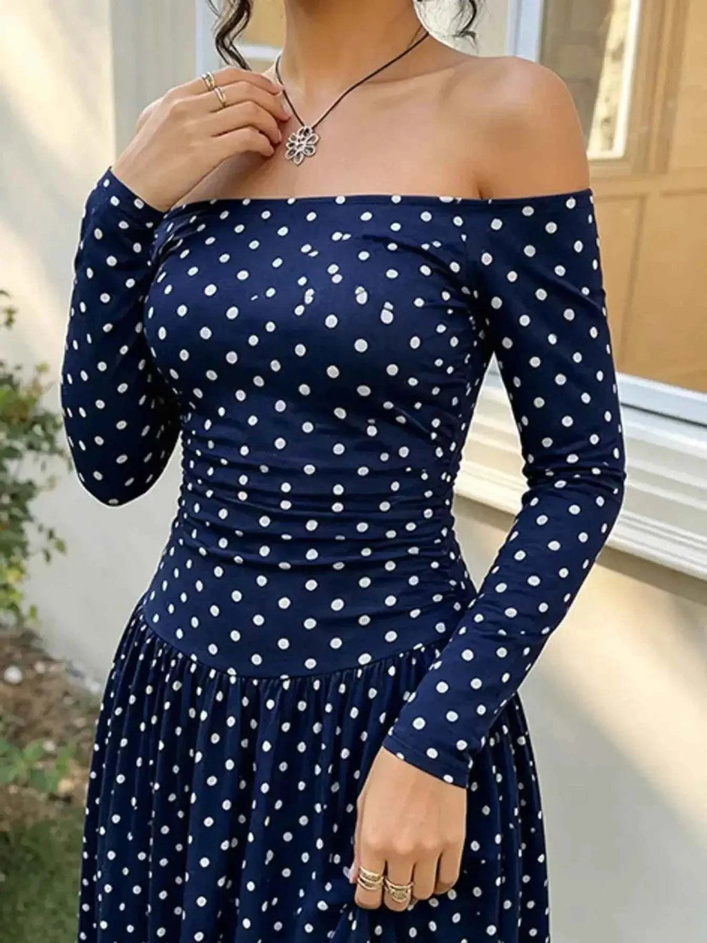 Off-the-Shoulder Maxi Dress in navy blue with white polka dots, featuring long sleeves and a fitted bodice with a flowing skirt.