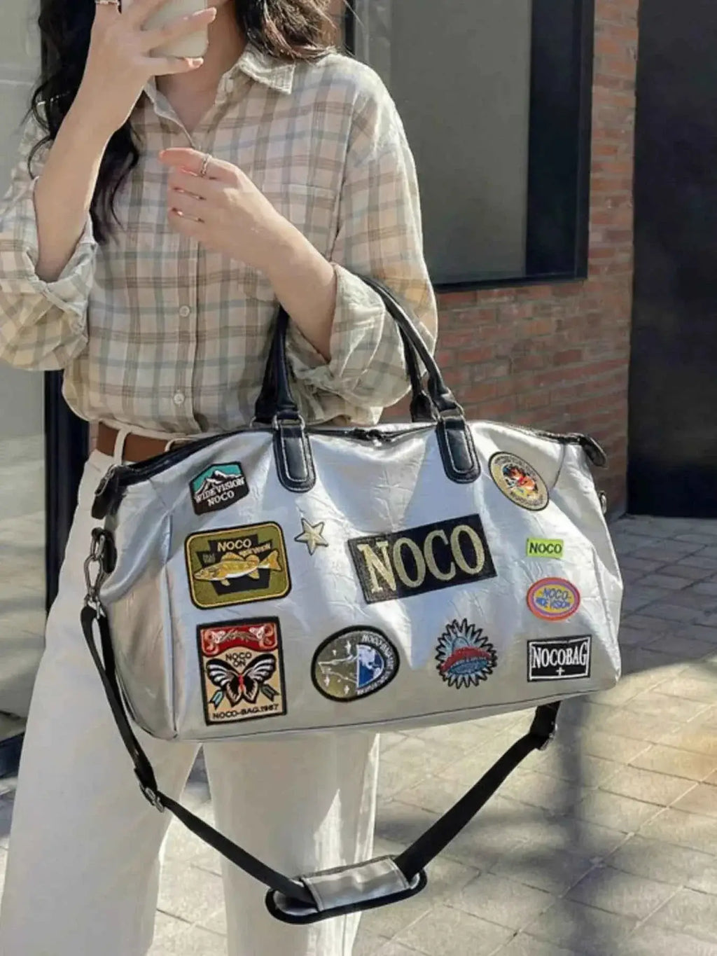 Patchwork Embellished Travel Bag in shiny silver PU leather with black handles and multiple colorful embroidered patches