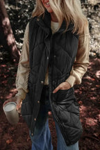 Black quilted pocketed zipper and button vest with a high collar worn over a beige sweater and blue jeans outdoors