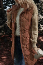 Pocketed Zipper and Button Vest sleeveless thick brown quilted polyester with snap buttons and side pockets worn over cream cable knit sweater