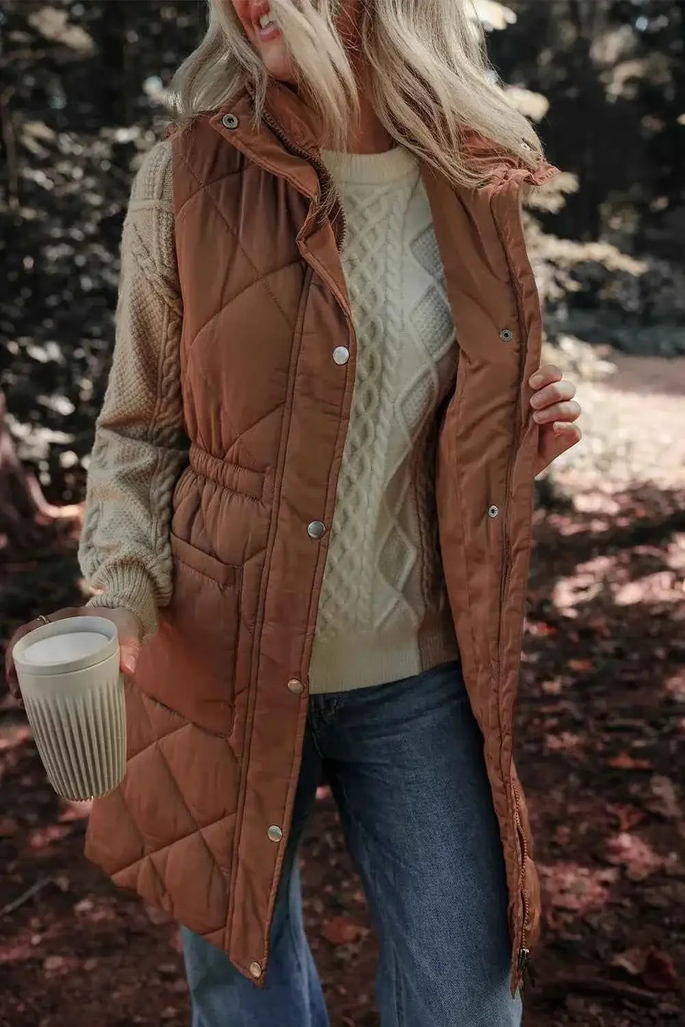 Pocketed Zipper and Button Vest in brown quilted polyester with snap buttons and zipper closure, worn over a cream knitted sweater