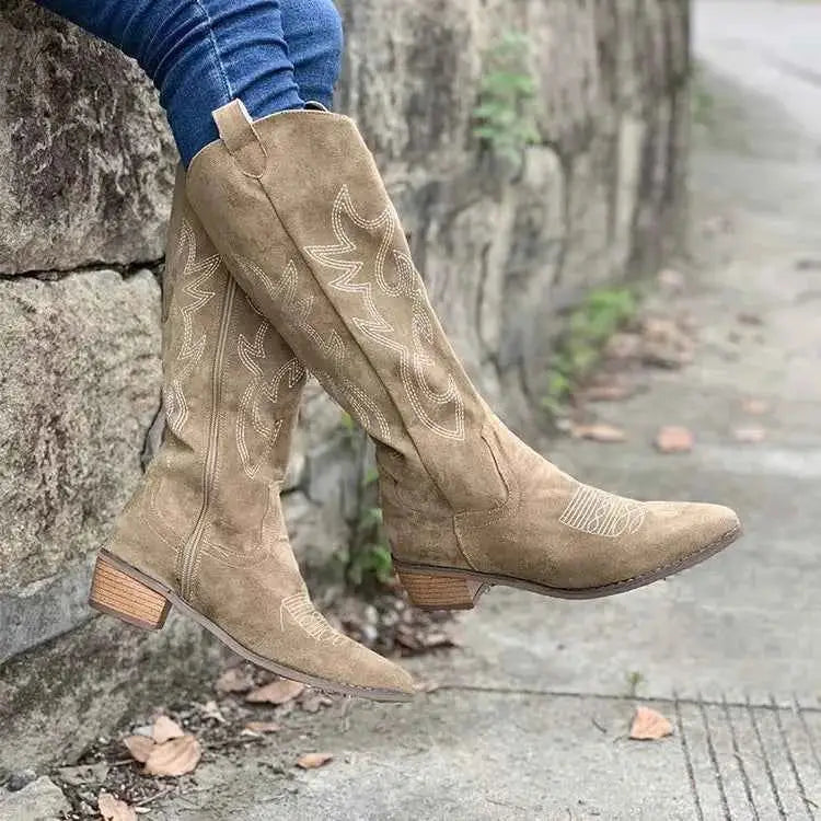 Point Toe Block Heels boots in tan suede with decorative stitching and mid-height wooden block heels worn with blue jeans.