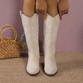 White suede knee-high boots with a subtle snake pattern and a v-shaped top, featuring Point Toe Block Heels.