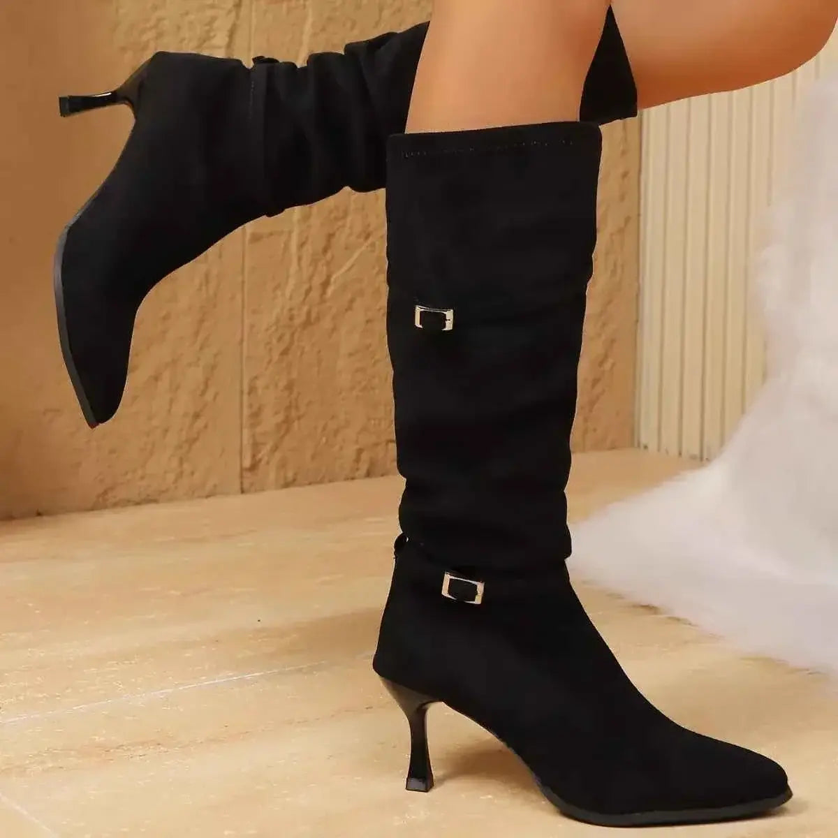 Black suede knee-high boots with pointed toes, slim high heels, and decorative silver buckles, featuring Point Toe Kitten Heels style.
