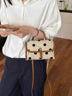 Polka Dot Crossbody Bag in beige polyester with black polka dots and brown leather trim held by person in white blouse