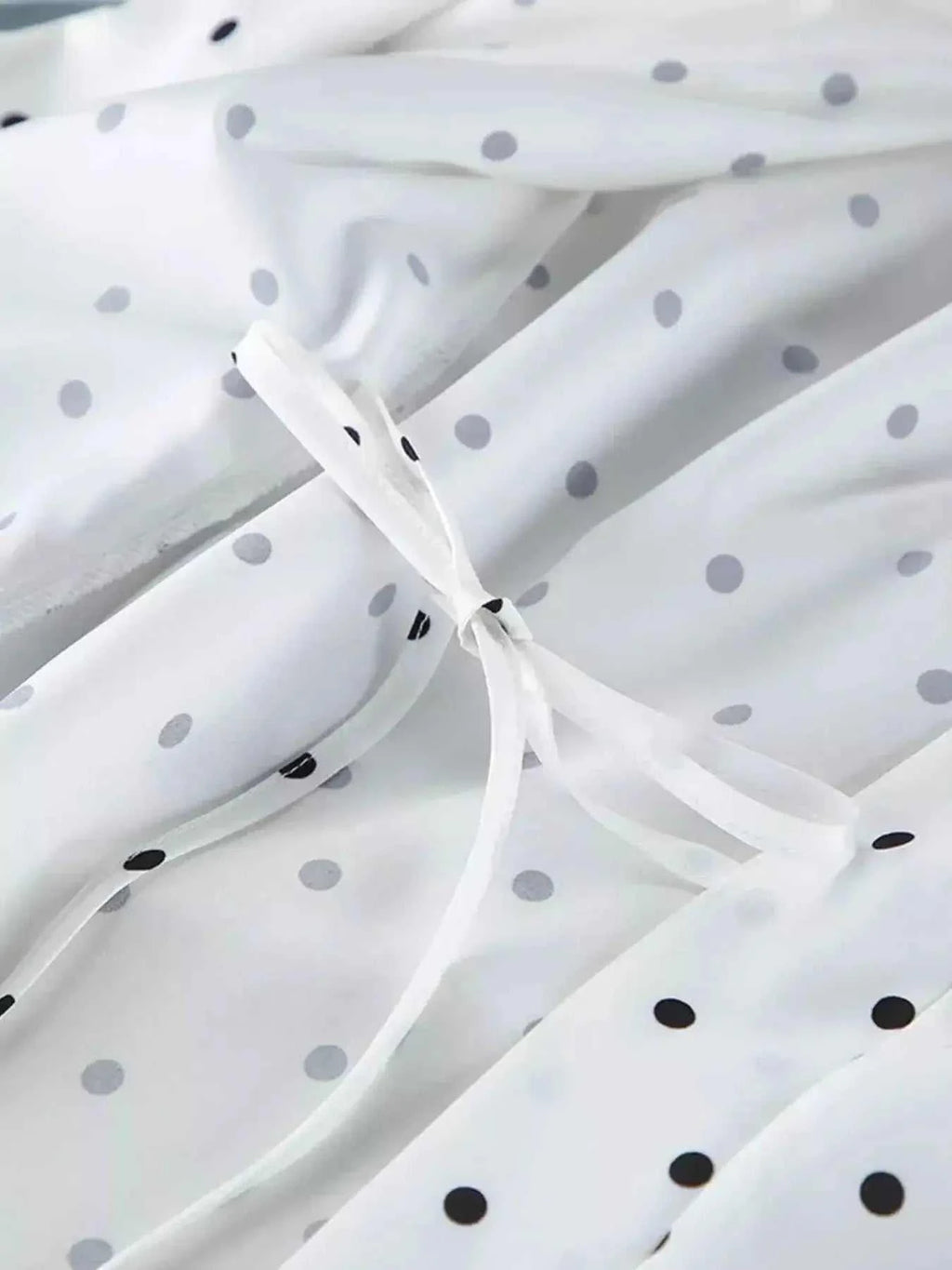 White fabric with black and gray polka dots featuring delicate tied ribbon detail showcasing Polka Dot Lace Trim design