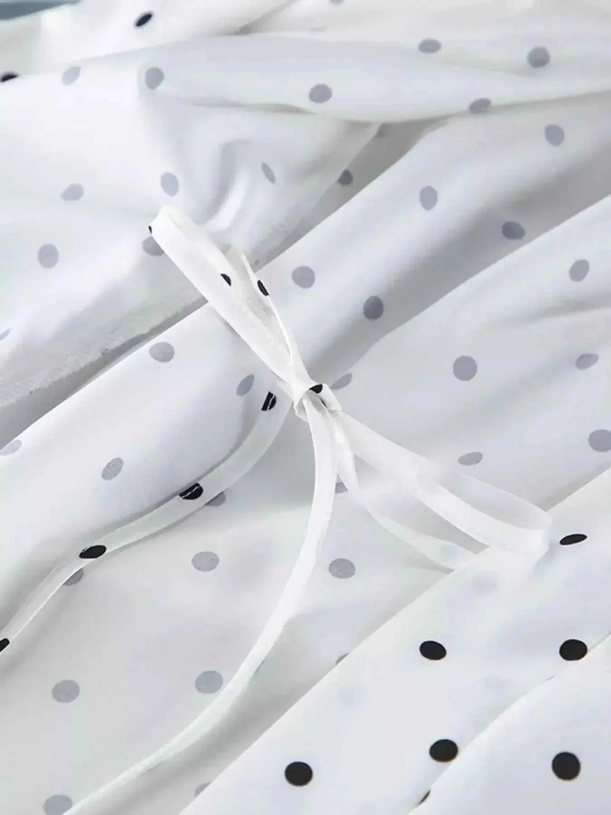 White fabric with black and gray polka dots featuring delicate tied ribbon detail showcasing Polka Dot Lace Trim design
