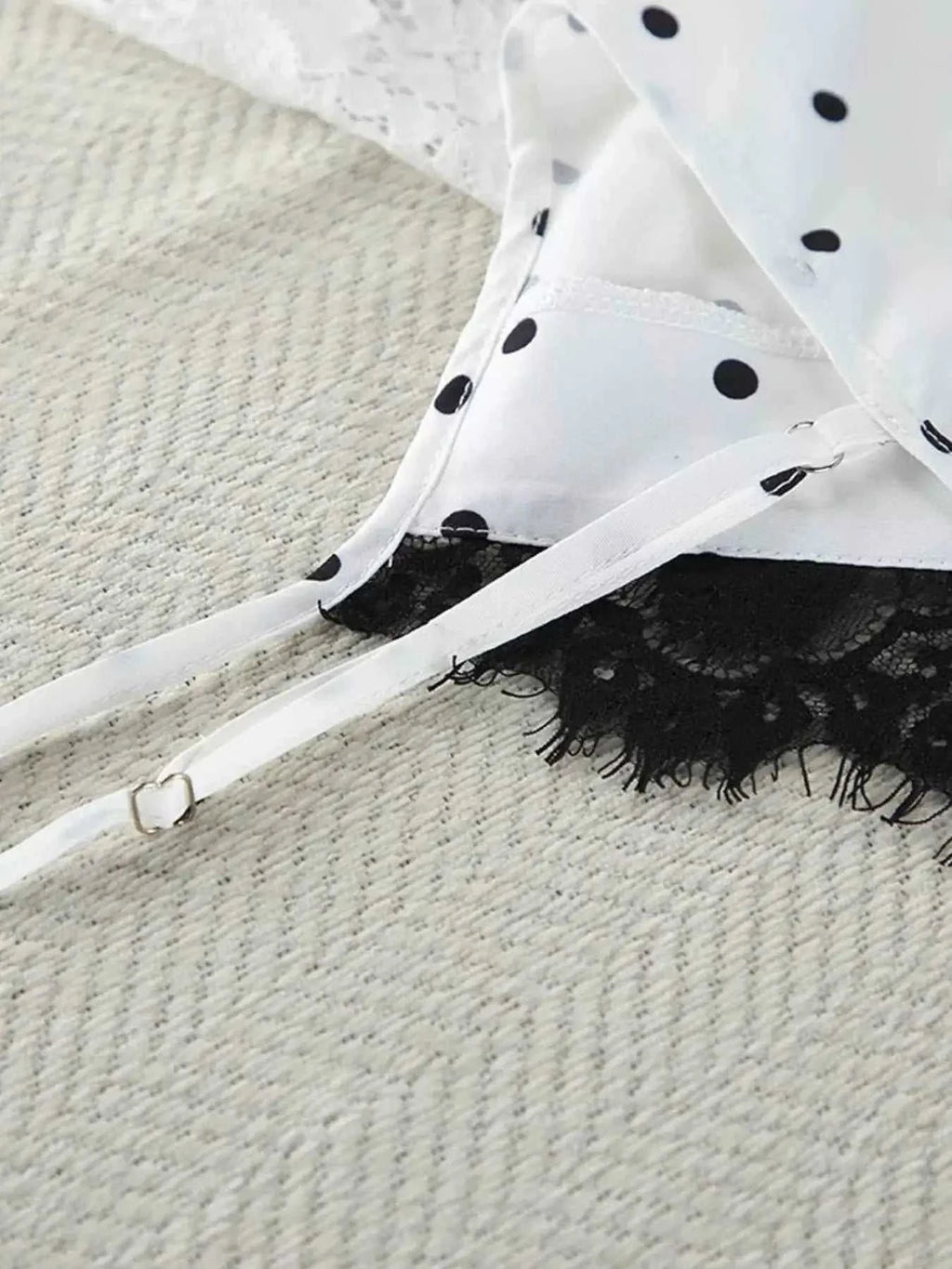 White cami top with black polka dots and black lace trim featuring adjustable straps and delicate fabric texture in Polka Dot Lace Trim design