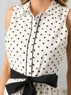 Polka Dot Sleeveless Midi Shirt Dress in white with black polka dots, buttoned front, collared neckline, and black waist belt tied in a bow