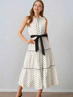 Polka Dot Sleeveless Midi Shirt Dress in white with black polka dots, featuring a buttoned front, tiered skirt, and black belt tied at waist