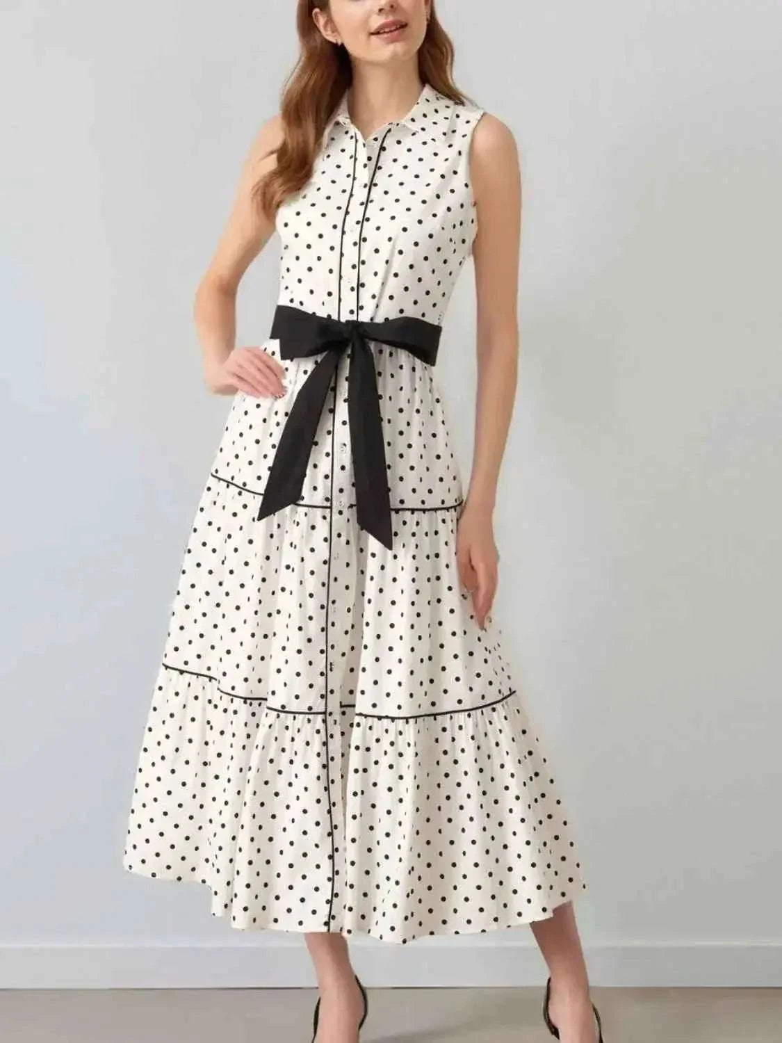 Polka Dot Sleeveless Midi Shirt Dress in white with black polka dots, buttoned front, tiered skirt, and black belt tied at waist