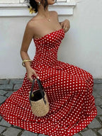 Polka Dot Strapless Maxi Dress in red with white polka dots, fitted bodice, and flowy skirt, accessorized with a wicker handbag