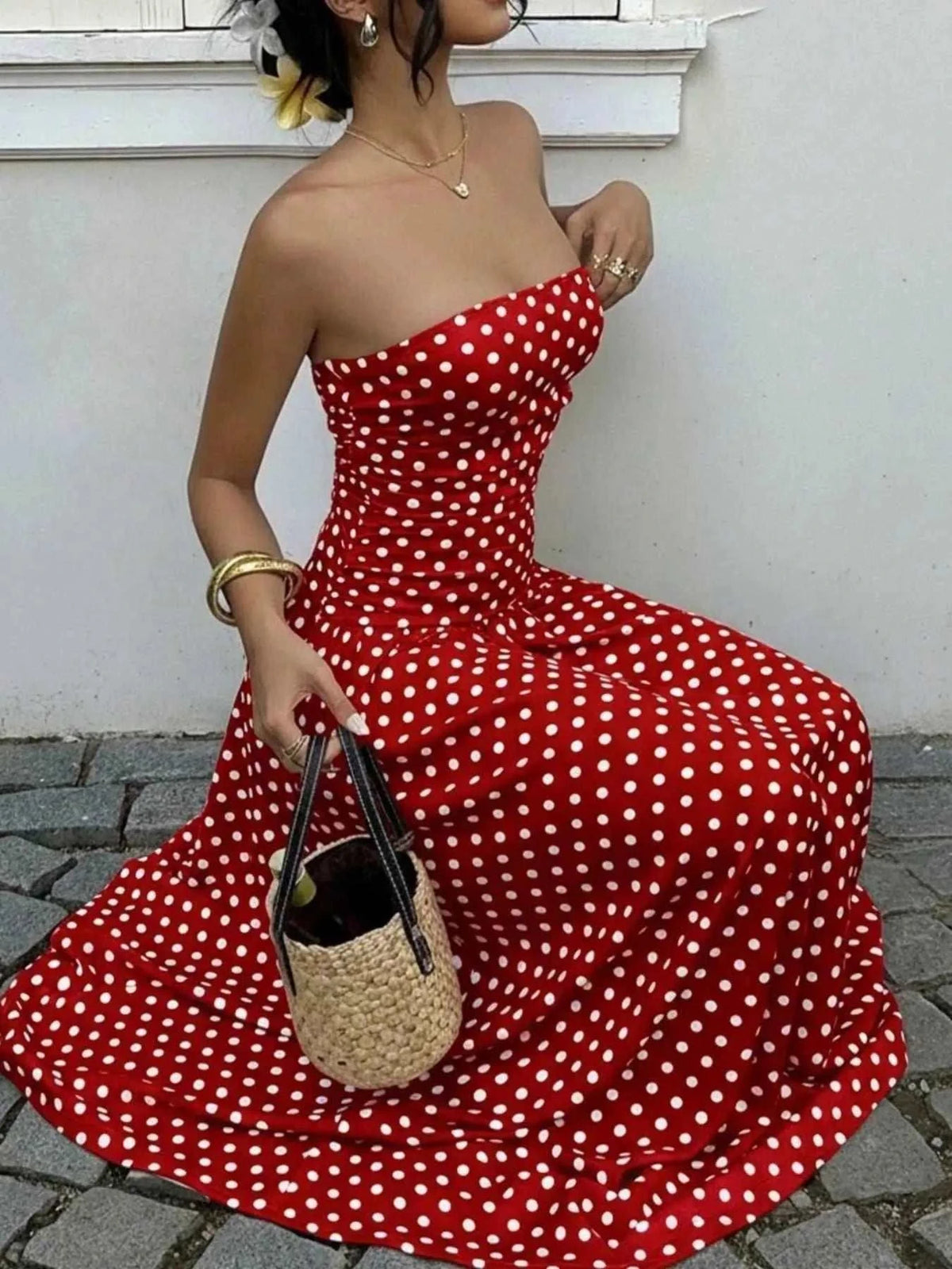 Polka Dot Strapless Maxi Dress in red with white polka dots, fitted bodice, and flowy skirt, accessorized with a wicker handbag