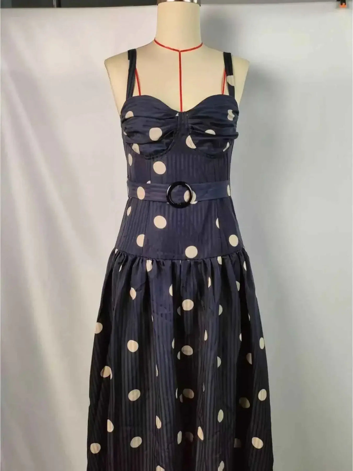 Polka Dot Sweetheart Neck Midi Dress in dark navy with white polka dots, featuring a fitted bodice, sweetheart neckline, belt with circular buckle, and flowy skirt