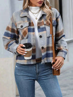 Polka Noir plaid button-up jacket in grey, blue, and brown with pockets and long sleeves, worn over a white turtleneck