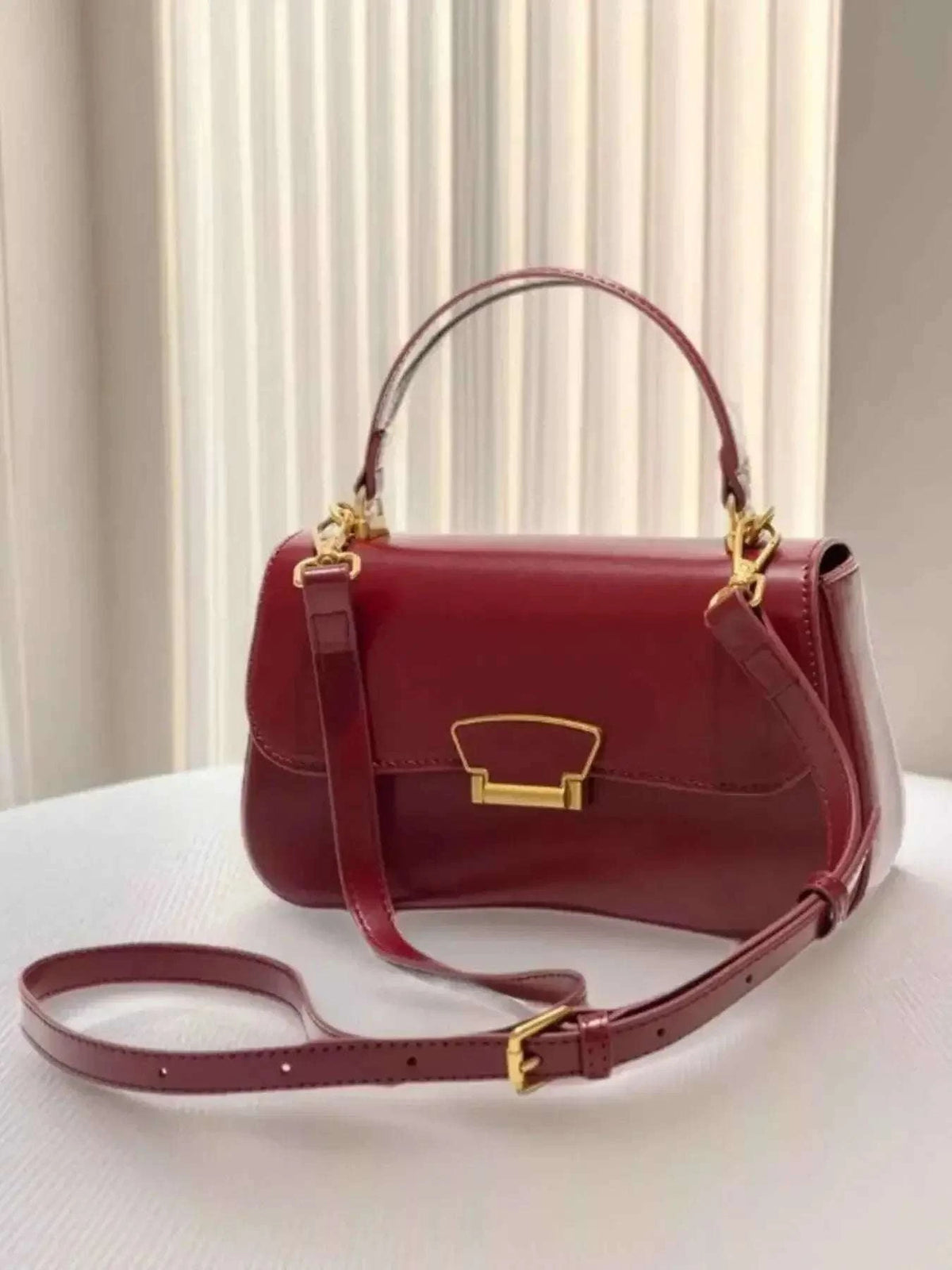 PU Leather Crossbody Bag in burgundy with gold-tone hardware, featuring a top handle and adjustable strap design.