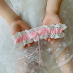 Sexy Lace Flower bridal garter belt with white lace, pink satin ribbon, and crystal embellishment held by hands