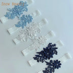 Two pairs of Sexy Lace Flower wedding garter belts in blue and black lace with floral embroidery and pearl accents on white lace bands