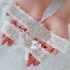 Sexy Lace Flower white lace wedding garter set featuring floral patterns with crystal and pearl embellishments held in hands