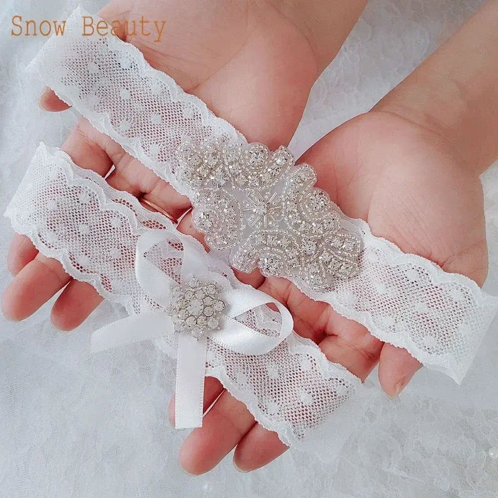 Sexy Lace Flower white lace wedding garter set featuring floral patterns with crystal and pearl embellishments held in hands