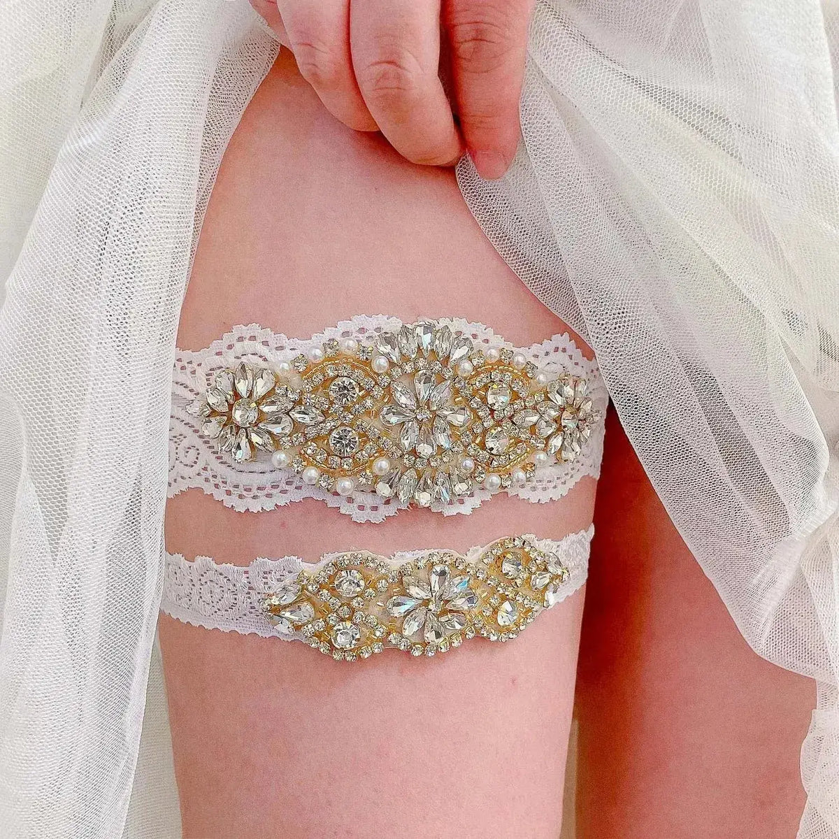 Two white wedding garter belts with lace, crystal, pearl, and flower embellishments worn on thigh under sheer fabric, Sexy Lace Flower
