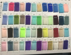 Color swatches of sheer fabric samples in various shades including pink, purple, blue, green, and beige pinned on a white board