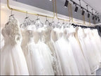 Collection of white short wedding dress gowns with lace and tulle details hanging on gold rack in bridal shop