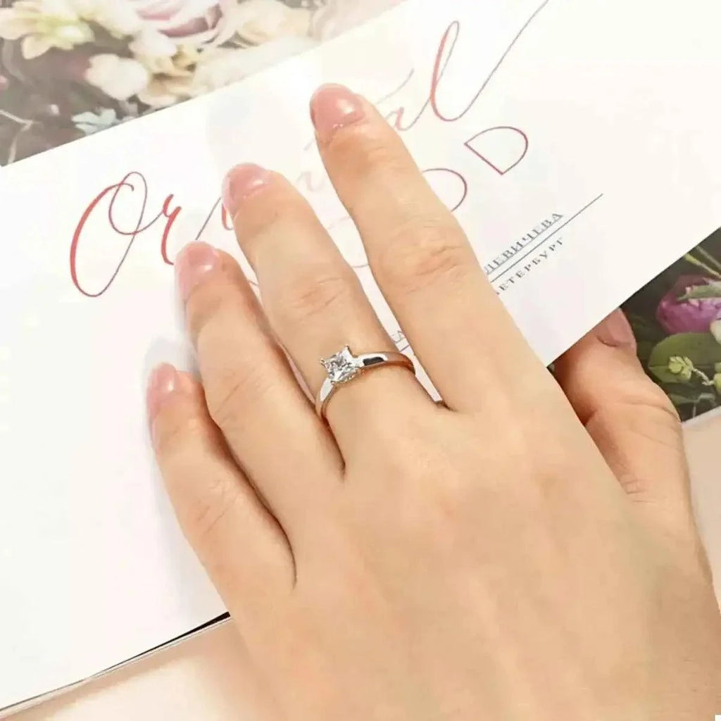 Silver-Plated Minimalist Ring featuring a silver-plated copper band with a clear square zircon gemstone centerpiece on a finger.