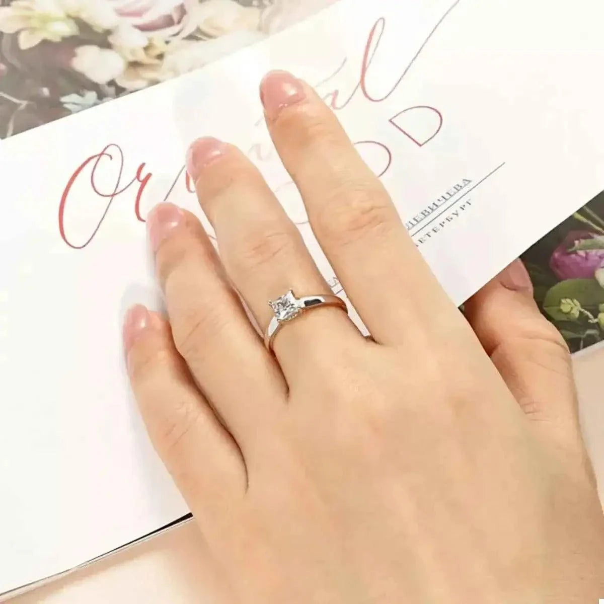 Silver-Plated Minimalist Ring featuring a silver-plated copper band with a clear square zircon gemstone centerpiece on a finger.