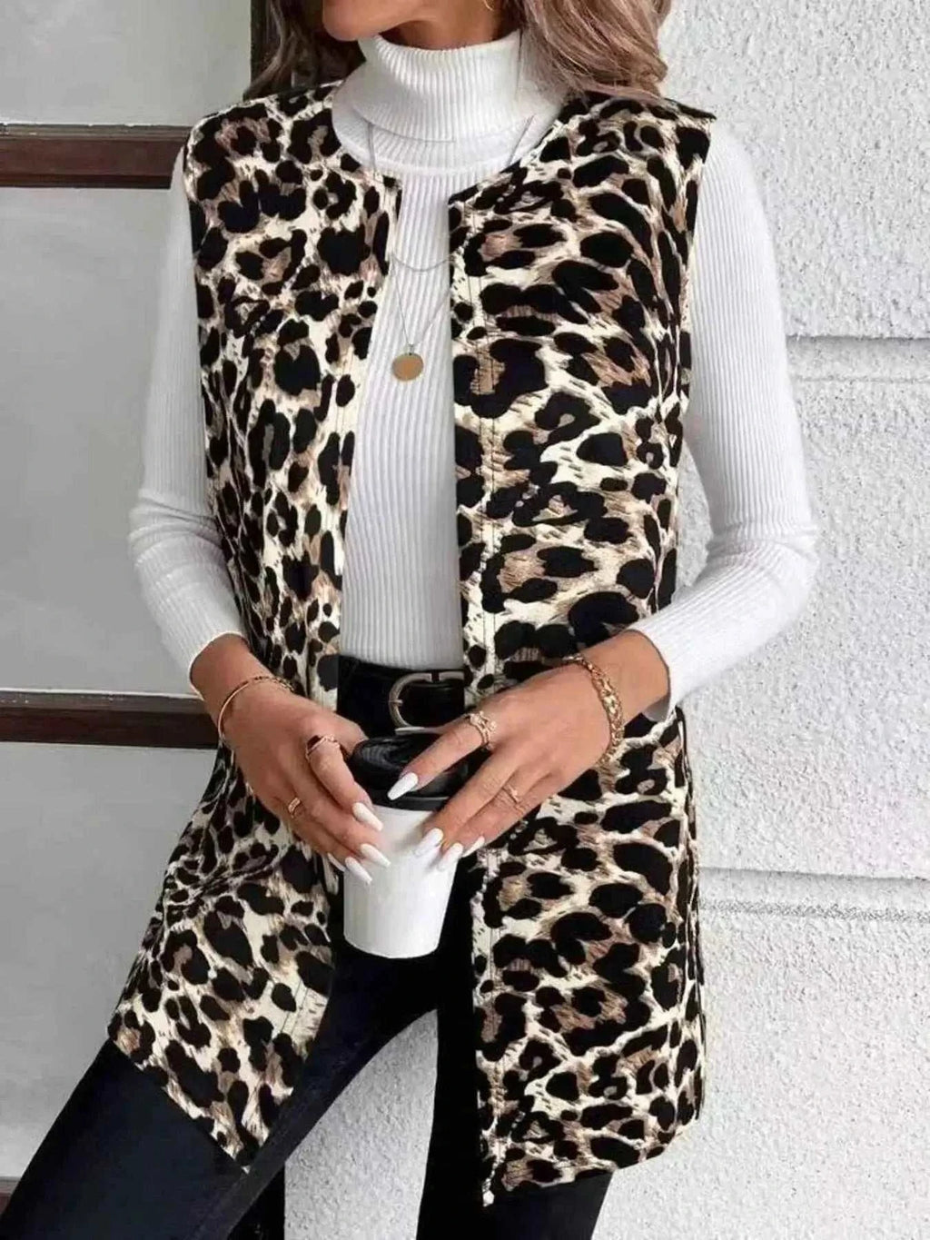 Sleeveless Leopard Print Vest in black and beige leopard pattern, worn over a white ribbed turtleneck sweater with front pockets and open front
