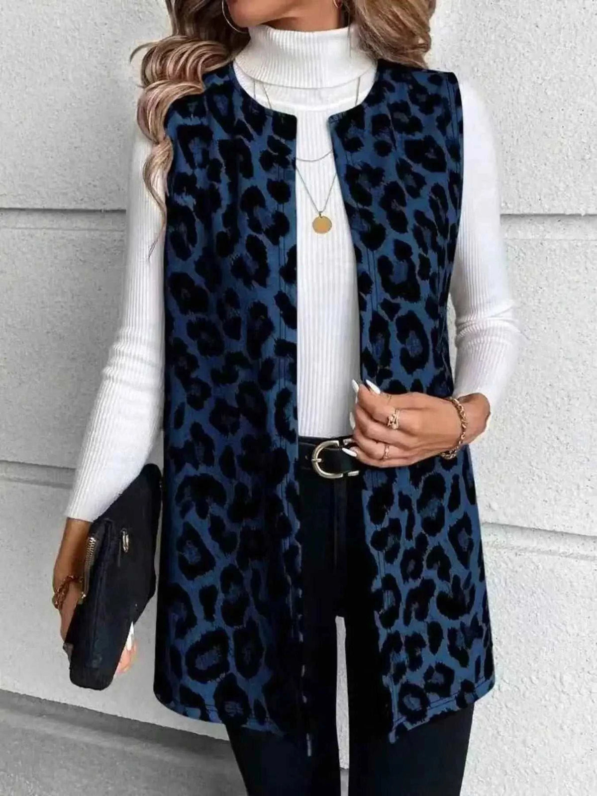 Sleeveless Leopard Print Vest in blue and black leopard pattern, sleeveless design with pockets worn over white ribbed turtleneck sweater