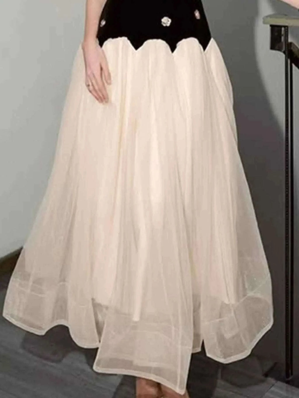 Sleeveless Tulle Maxi Dress featuring a flowing cream tulle skirt with a black bodice accented by white floral details.