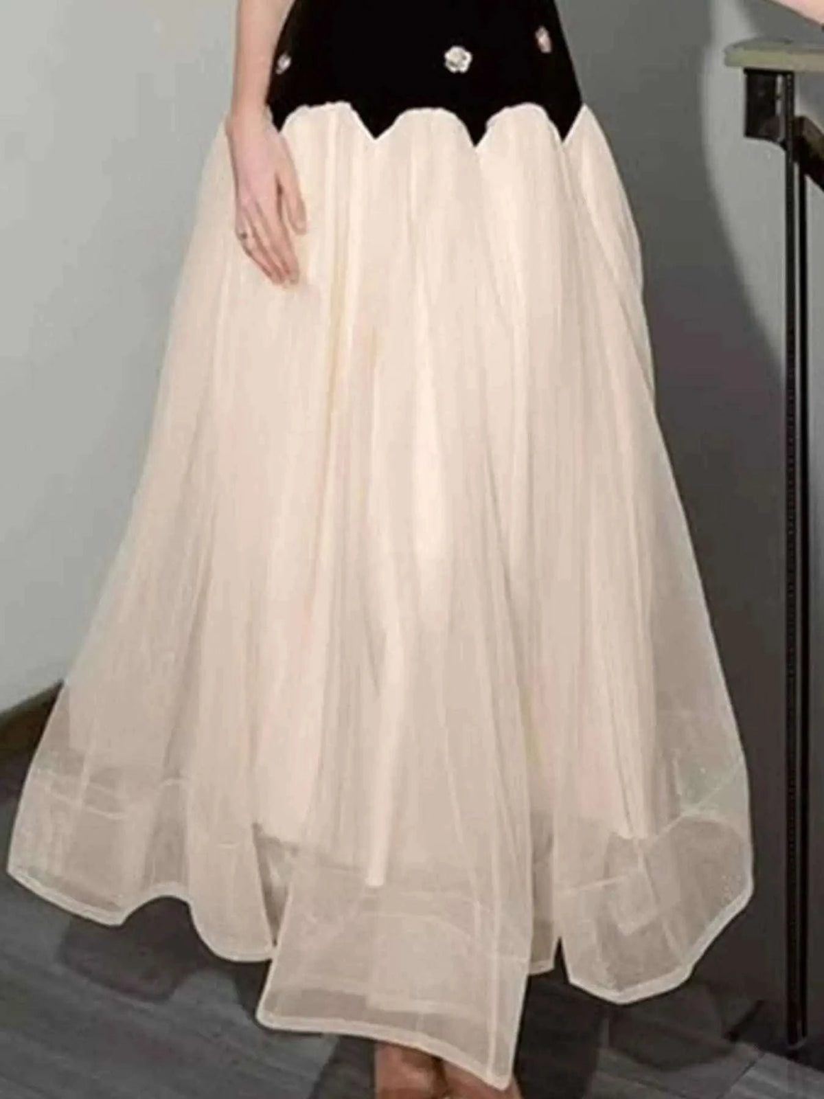 Sleeveless Tulle Maxi Dress featuring a flowing cream tulle skirt with a black bodice accented by white floral details.