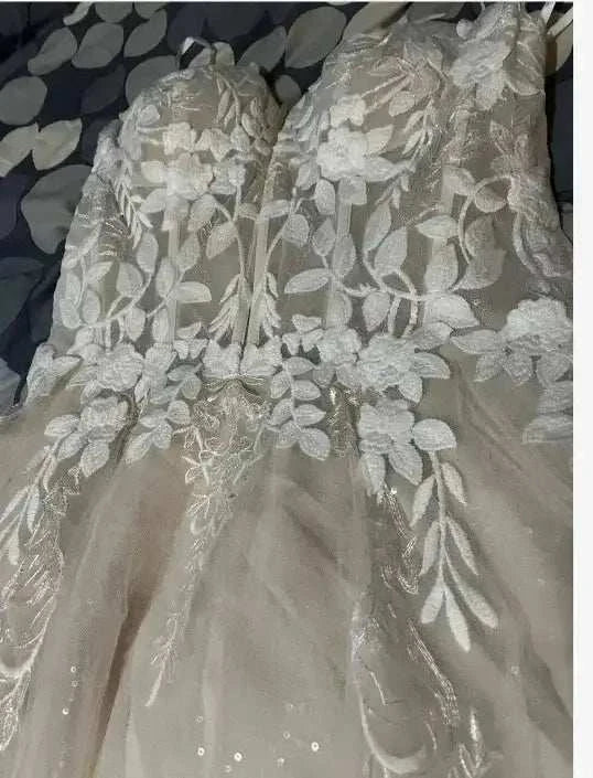 strapless V-neck wedding dress with white floral lace applique and sheer tulle skirt detailing