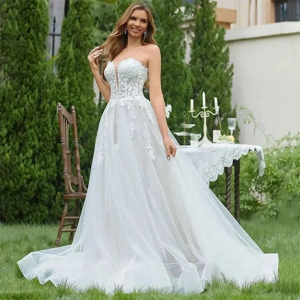 White strapless V-neck wedding dress with 3D floral lace applique and flowing tulle A-line skirt with sweep train