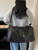 Large black Textured Leather Travel Bag made of PU leather with chevron pattern and dual handles carried by person
