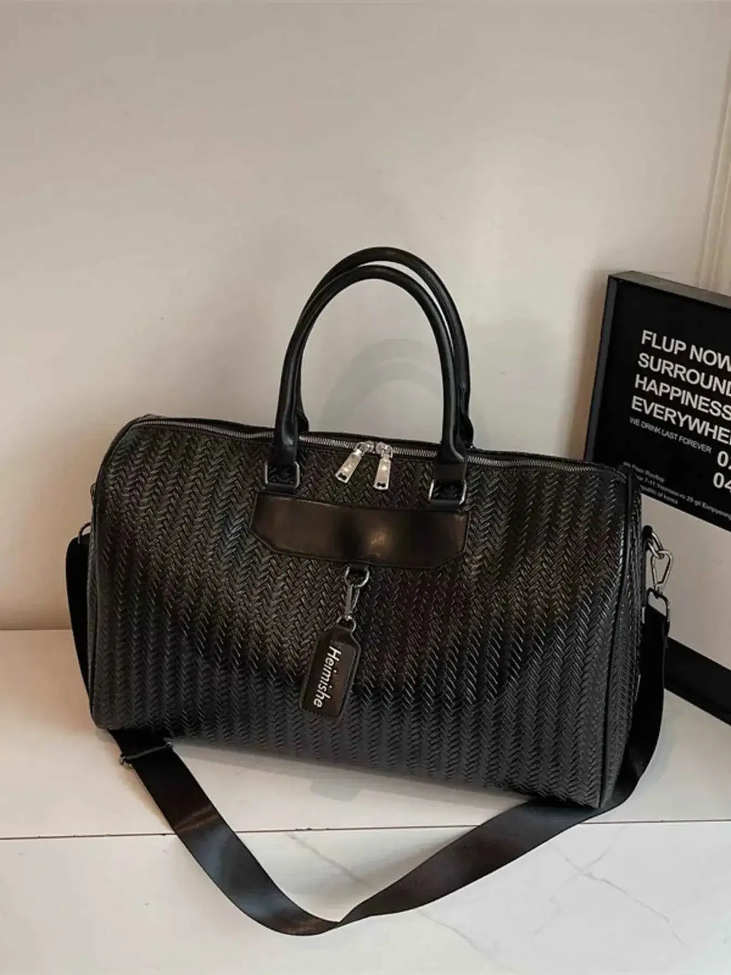 Black textured leather travel bag with woven pattern, PU leather material, dual handles, and a detachable shoulder strap
