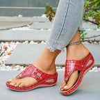 Red croc pattern Toe Post Wedge Sandals in PU leather with gray rubber wedge soles worn with ankle chain and light denim jeans