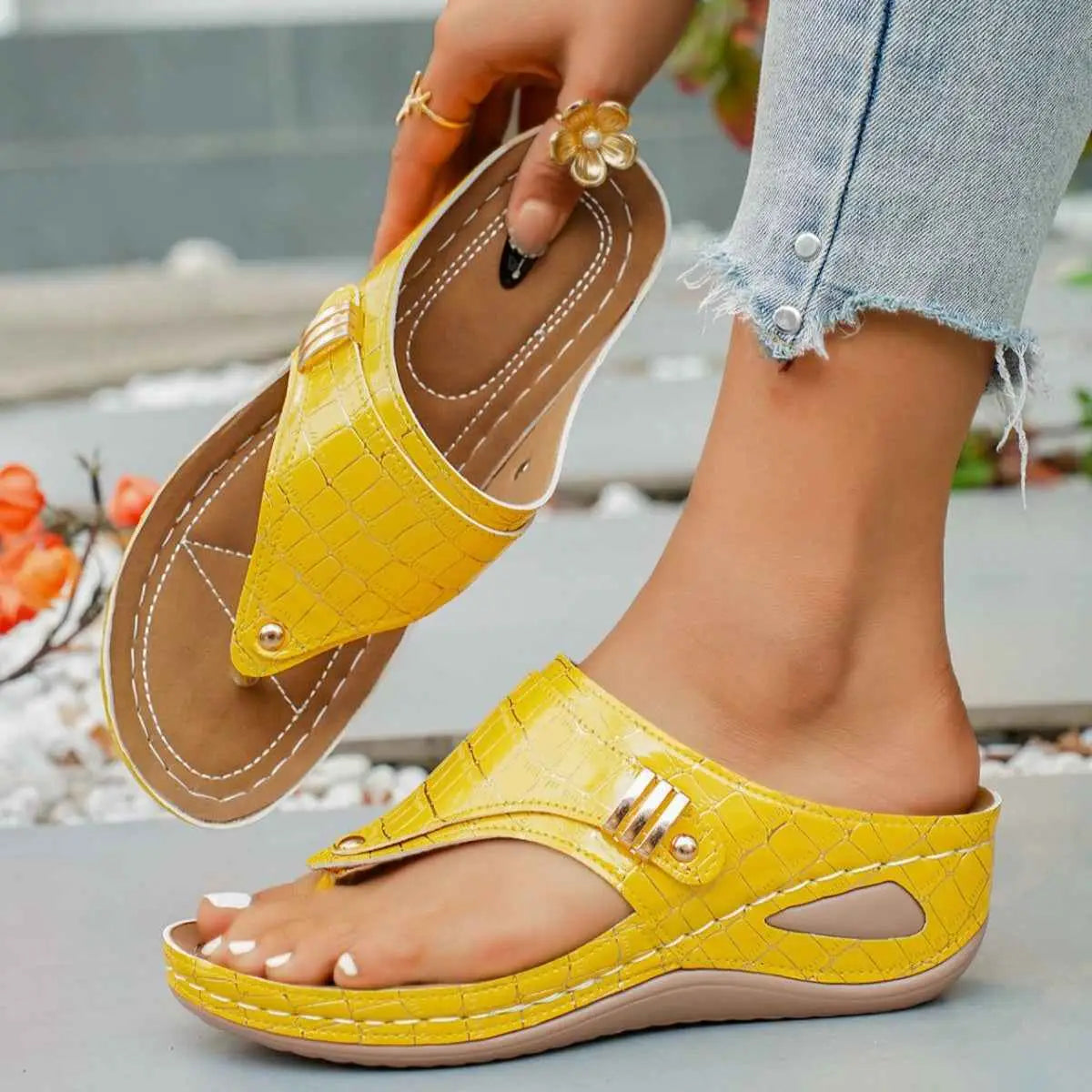 Yellow PU leather Toe Post Wedge Sandals with crocodile pattern, mid heel and rubber sole shown worn on foot and held by hand