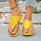 Toe Post Wedge Sandals in bright yellow PU leather with crocodile pattern and mid rubber wedge heels, worn with anklet and jeans