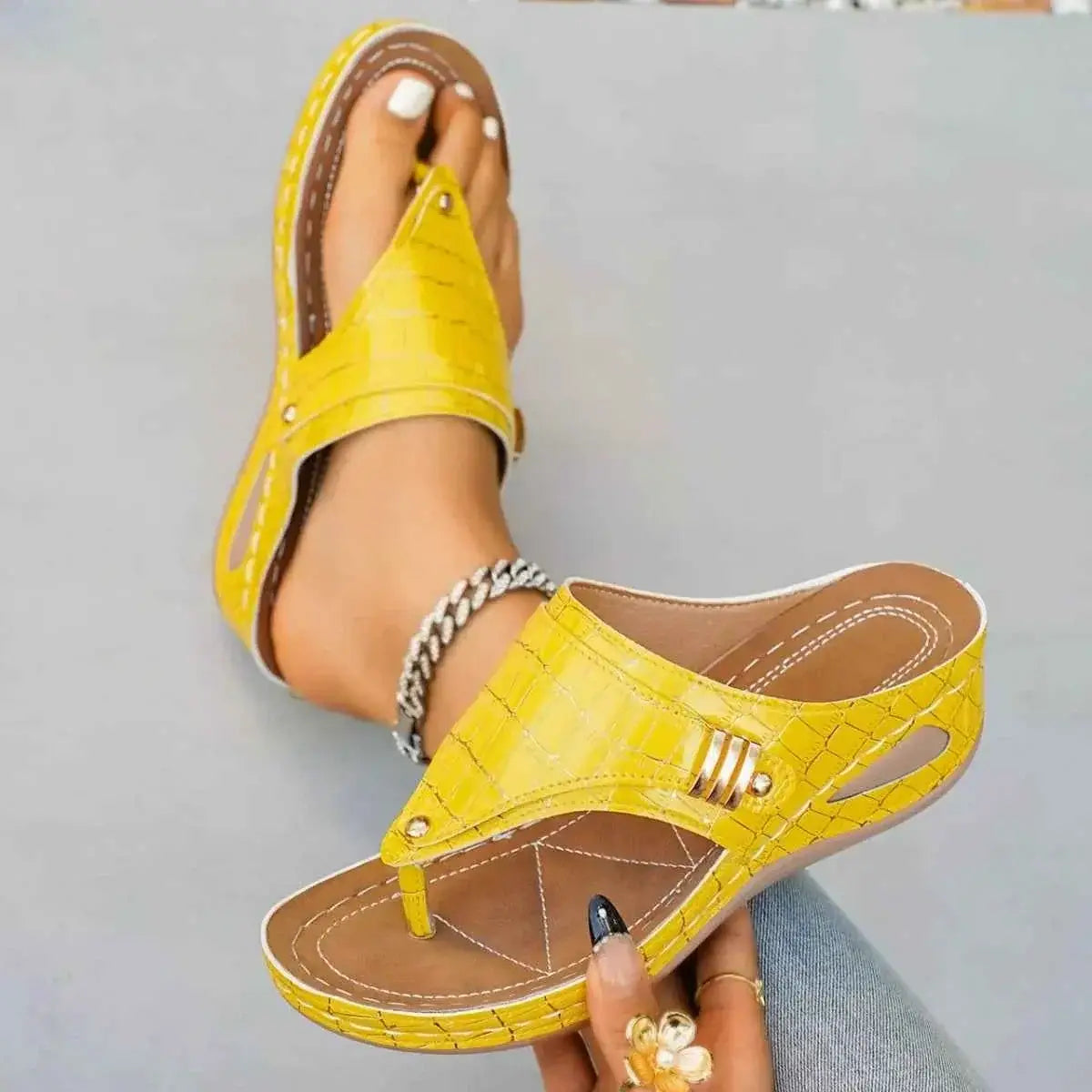 Yellow PU leather toe post wedge sandals featuring a faux crocodile pattern and mid heel, styled with an ankle chain