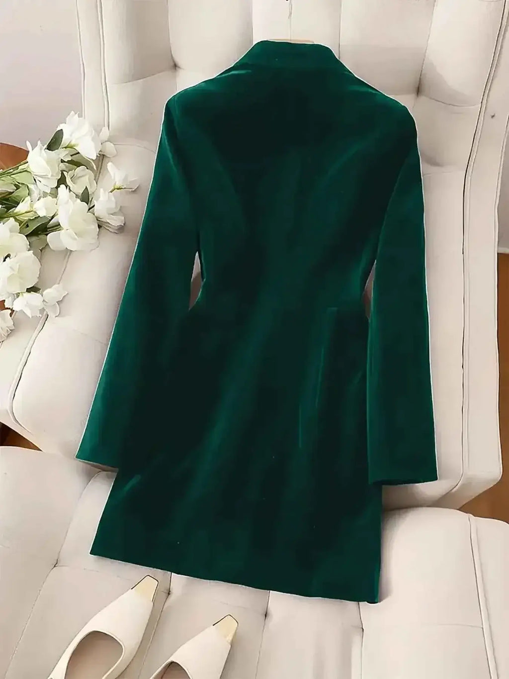 Velvet Double-Breasted Blazer in deep green velvet fabric with long sleeves and tailored fit, laid flat on a chair.