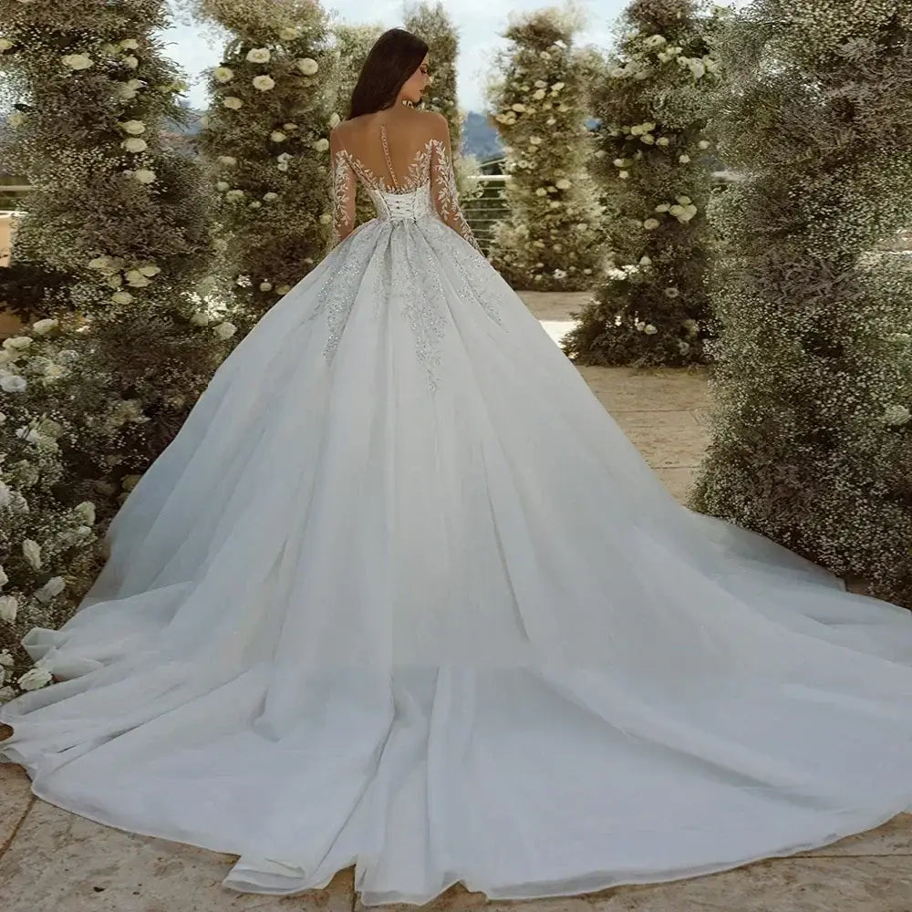 Wedding Dresses white ball gown with long lace sleeves, tiered tulle skirt, and intricate applique back detailing