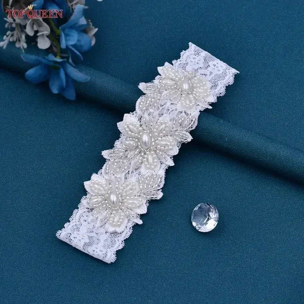 White lace Wedding Garter Belt featuring floral patterns decorated with pearl beads and crystals on a teal surface