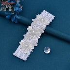 White lace Wedding Garter Belt featuring floral patterns decorated with pearl beads and crystals on a teal surface