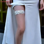 White lace Wedding Garter Belt with floral pattern and pearl bead accents worn on thigh under white bridal dress