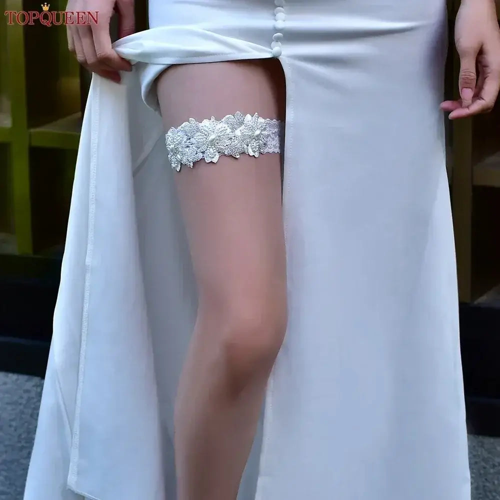 White lace Wedding Garter Belt with floral pattern and pearl bead accents worn on thigh under white bridal dress