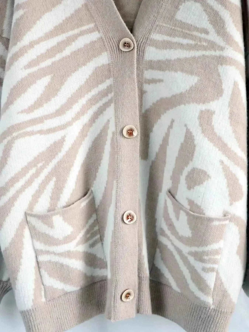 Zebra Print Button Up cardigan in beige and white with a buttoned front and two front pockets made of soft knit fabric