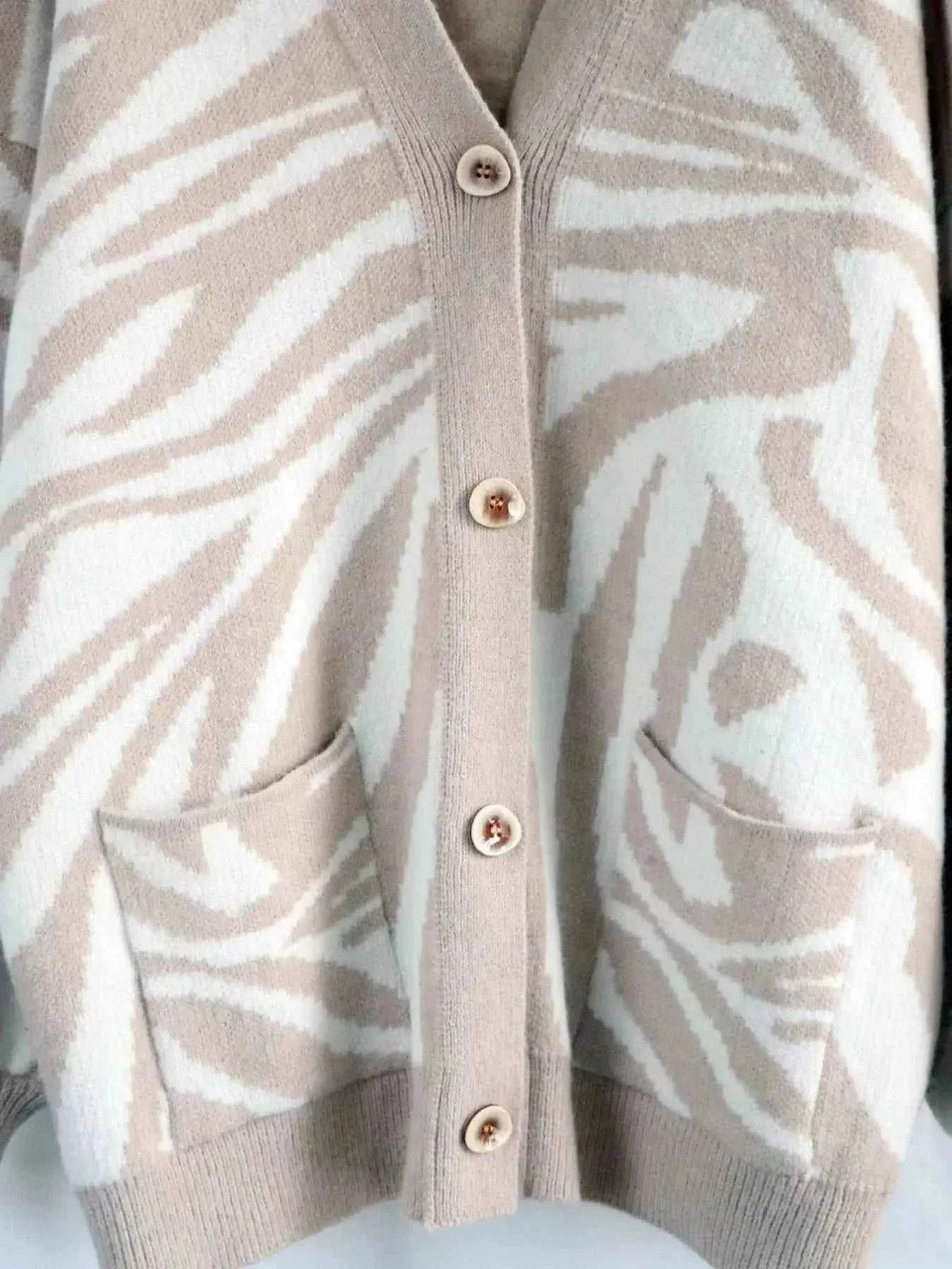 Zebra Print Button Up cardigan in beige and white with a buttoned front and two front pockets made of soft knit fabric